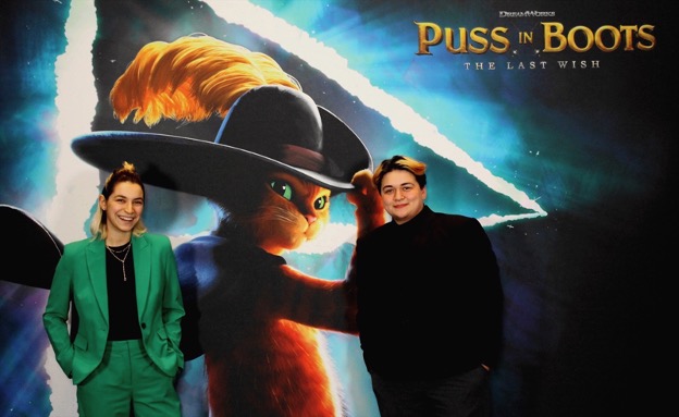Mac Lim (pictured right) standing with “Puss and Boots: The Last Wish” promotional poster.