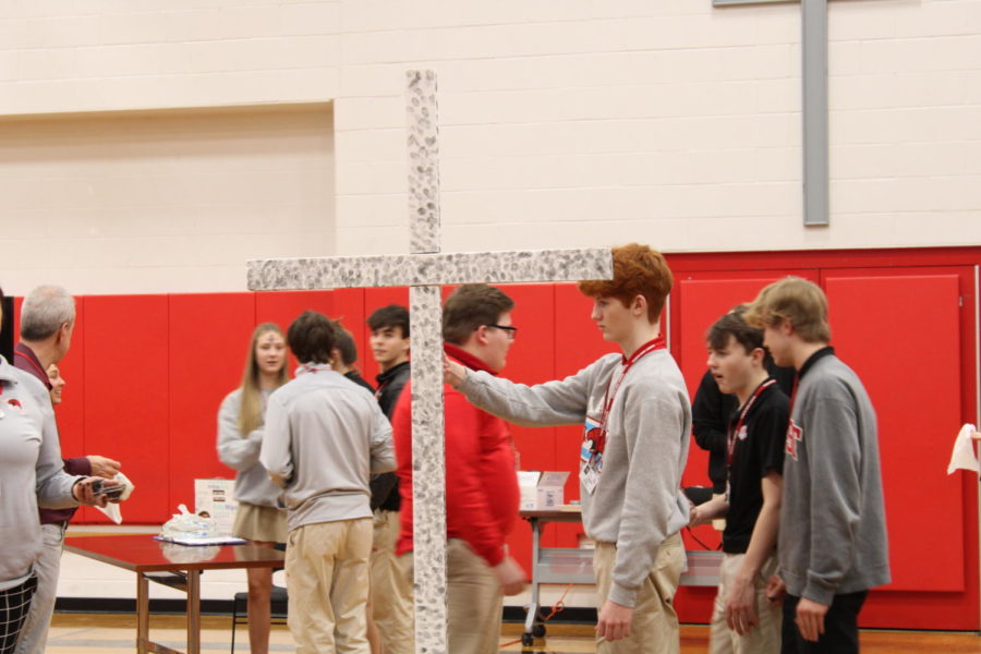 Marist students are putting their ash thumbprints on a cross during Ash Wednesday prayer service.