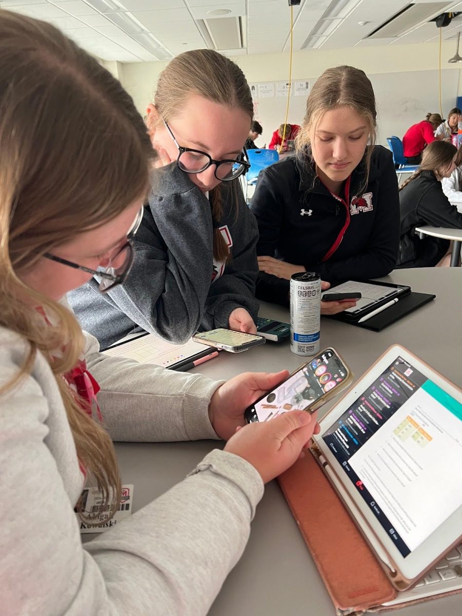 Abby Kowalski, Lily Yocum, and Aubree Waldrom focusing on their phones instead of school work