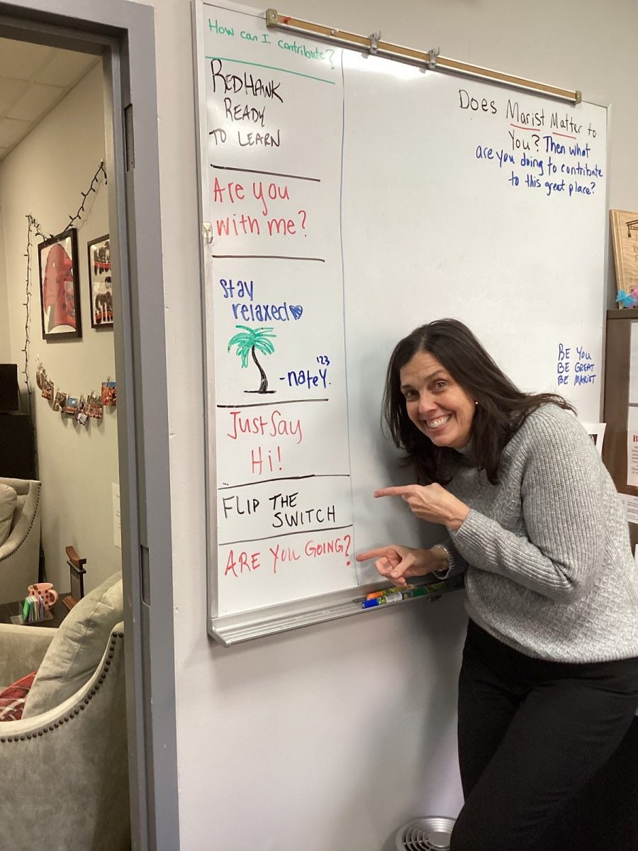 Principal Dunneback standing next to her white board with previous mottos 