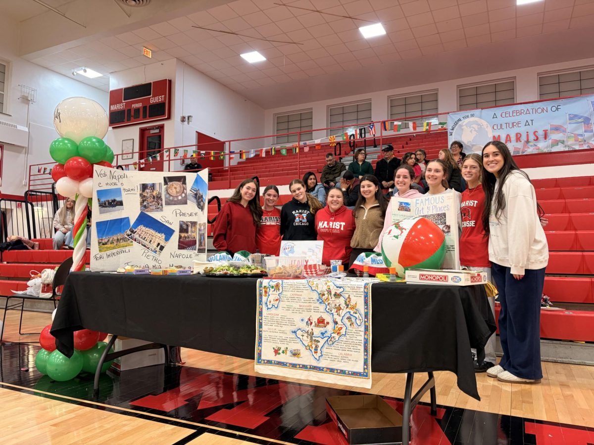 Students Ava Krueger, Maribel Blackburn, Mary Fortner, Jenna Manfre, Elsie Koch, Hannah McNeela, Isabella Scalise, Sofia McQuaid, Charlotte Consiglio standing behind one of the showcase tables representing Italy
